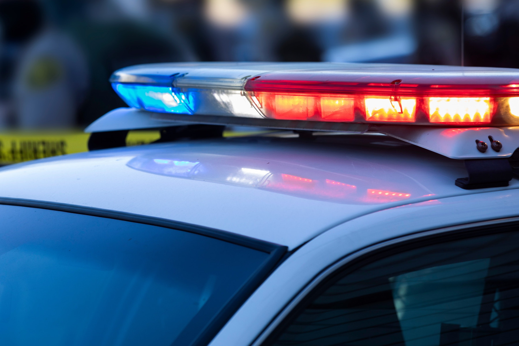 Blue and red lights flash on top of a white police car.