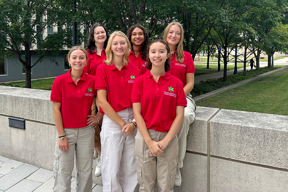 Six psychology student ambassadors standing outside of Psychology Building and wearing red shirts