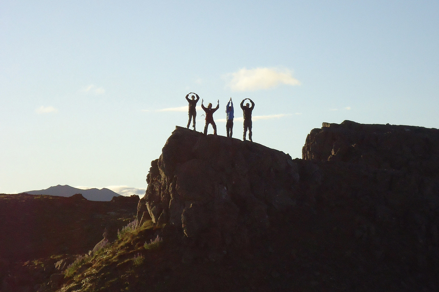 A group of students silhouetted while doing the O-H-I-O pose on top of a cliff