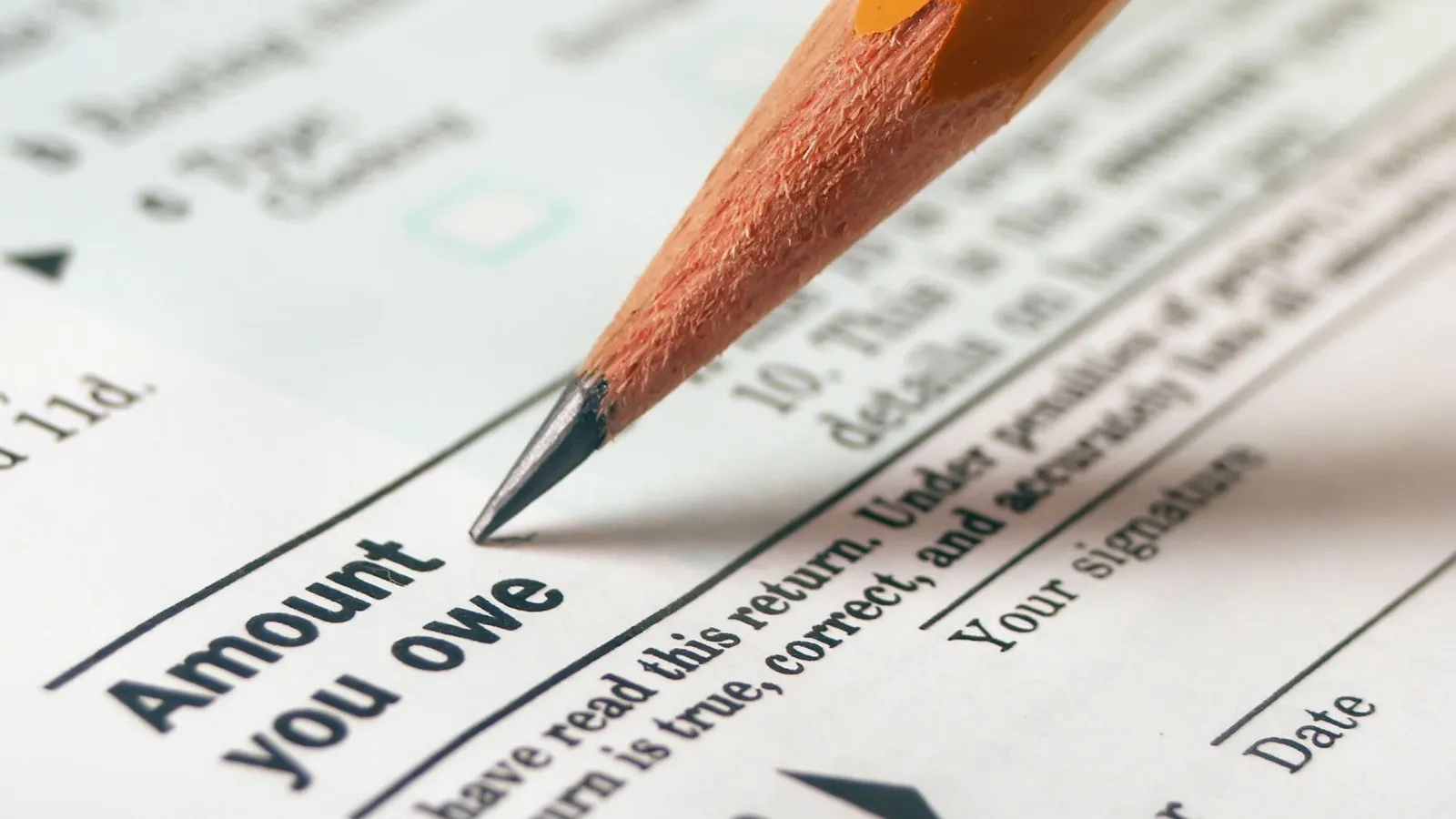 Close up of a pencil filling in the "Amount You Owe" section of a tax form.