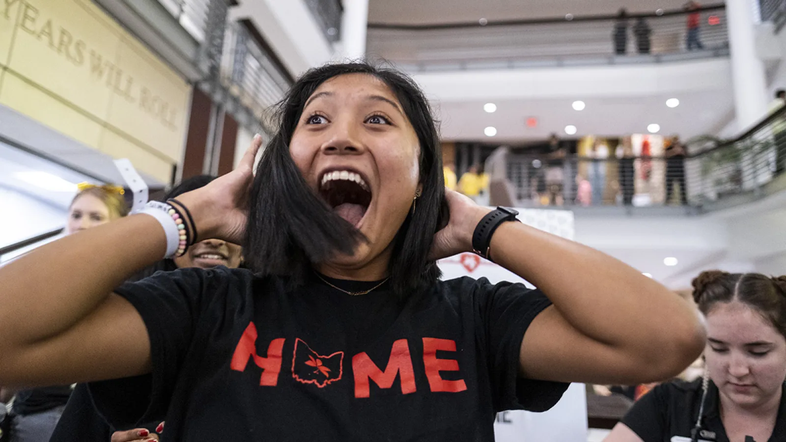 A woman wearing a "Home" shirt smiles after her hair is cut inside the Union.