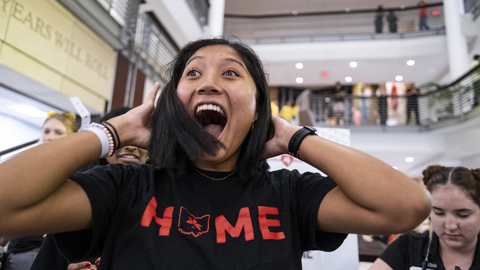 A woman wearing a "Home" shirt smiles after her hair is cut inside the Union.