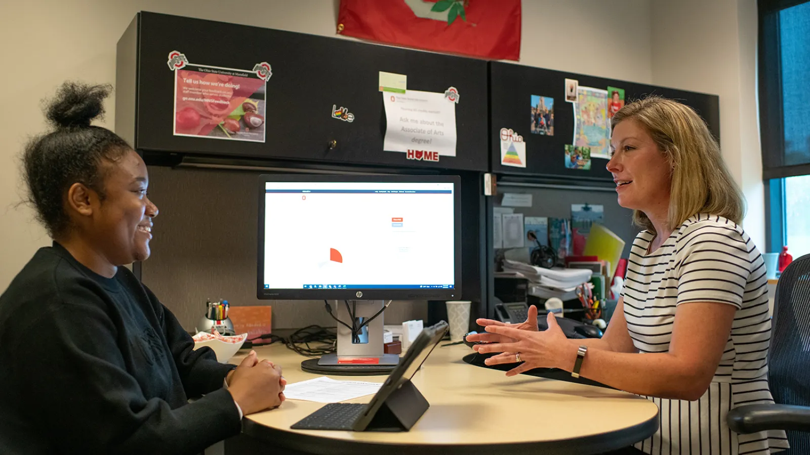 An advisor and student sit at a desk and talk