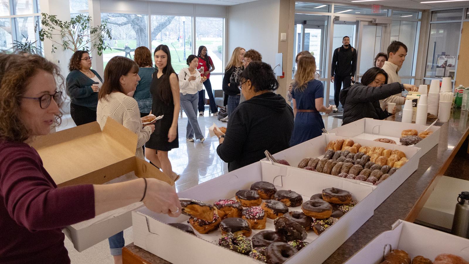 Students crowded in the Psychology Building lobby around several boxes of donuts