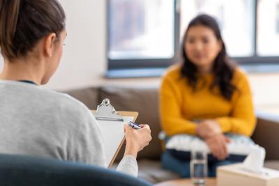 A therapist with a clipboard sits in an office with a patient.