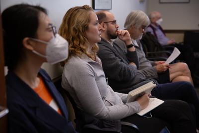 A row of seated people listen attentively during a presentation.