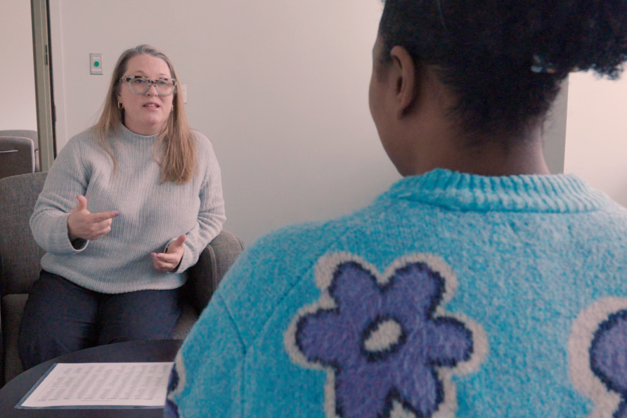 A therapist speaks to a client as the two of them sit opposite each other in a room