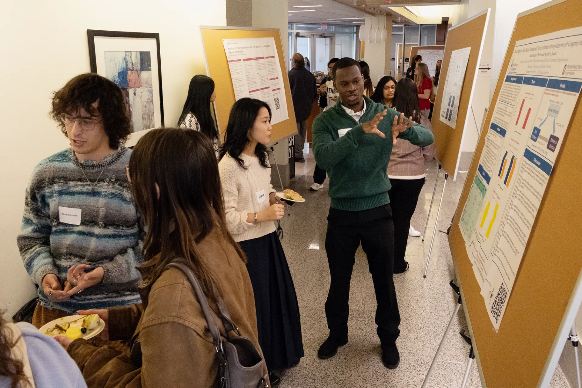 A student presents a research poster in the crowded hallway of the Psychology Building