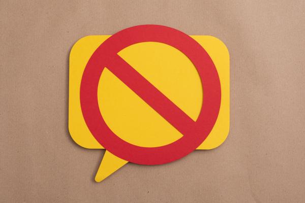 A yellow speech bubble with a red line through it canceling it out.
