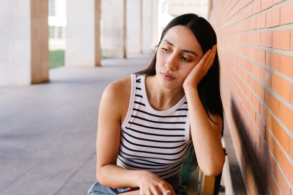 Woman in a striped tank top rests her head on her hand.