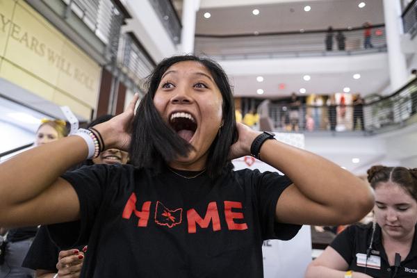 A woman wearing a "Home" shirt smiles after her hair is cut inside the Union.