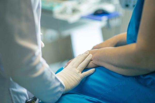 A doctor touches a patient's hand in an exam room