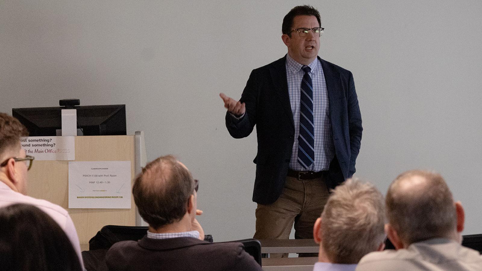 Joseph Uscinski lectures in front of a seated audience in a classroom.
