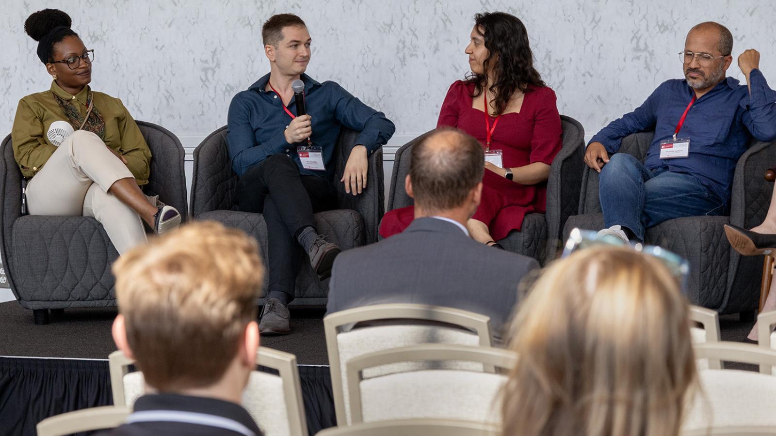 Four speakers sitting on a stage during a panel discussion