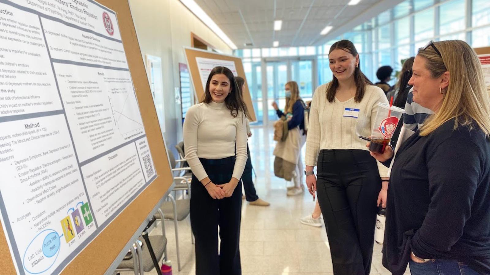 Student presents her research poster to others
